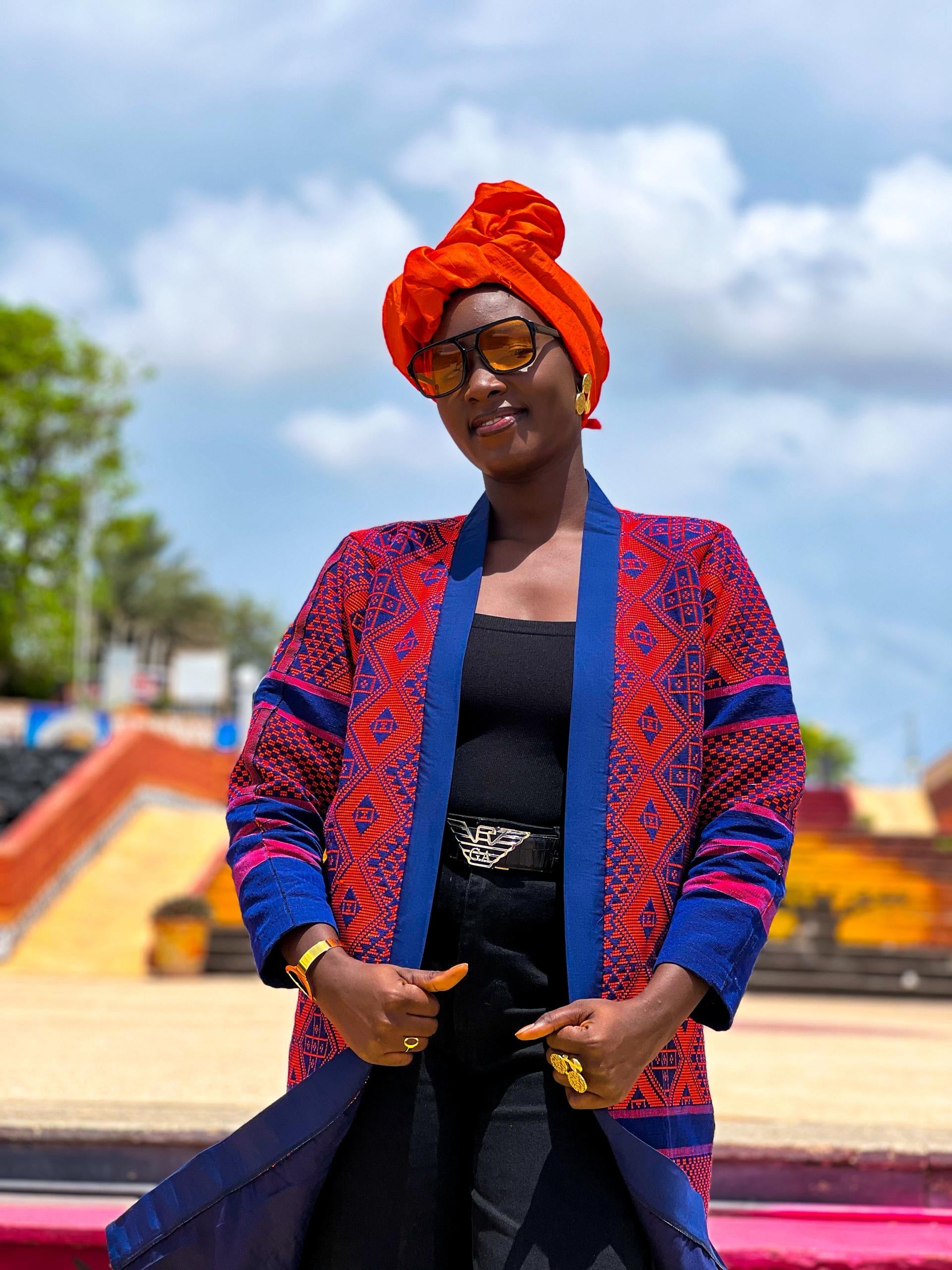 Woman wearing Kanoo Hand Woven Jacket with geometric patterns in vibrant colors, showcasing Senegalese heritage.